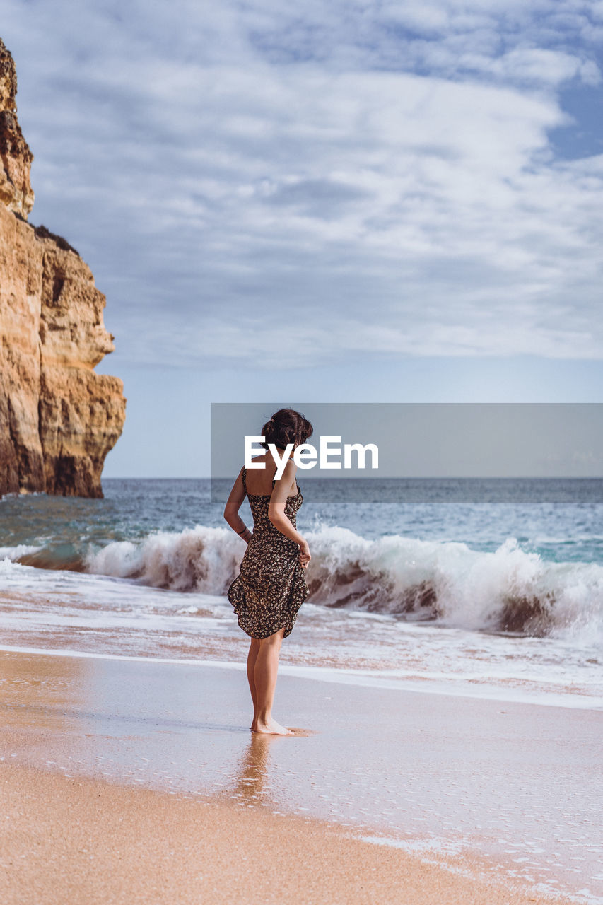 Full length of woman standing on beach against sky