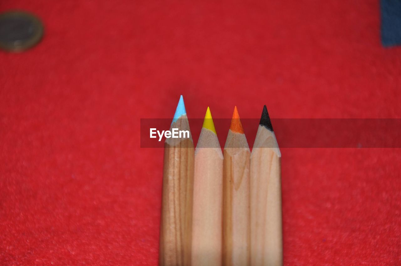 red, pencil, no people, close-up, writing instrument, colored pencil, sharp, indoors, multi colored, wood, still life, in a row, large group of objects, high angle view, education, red background