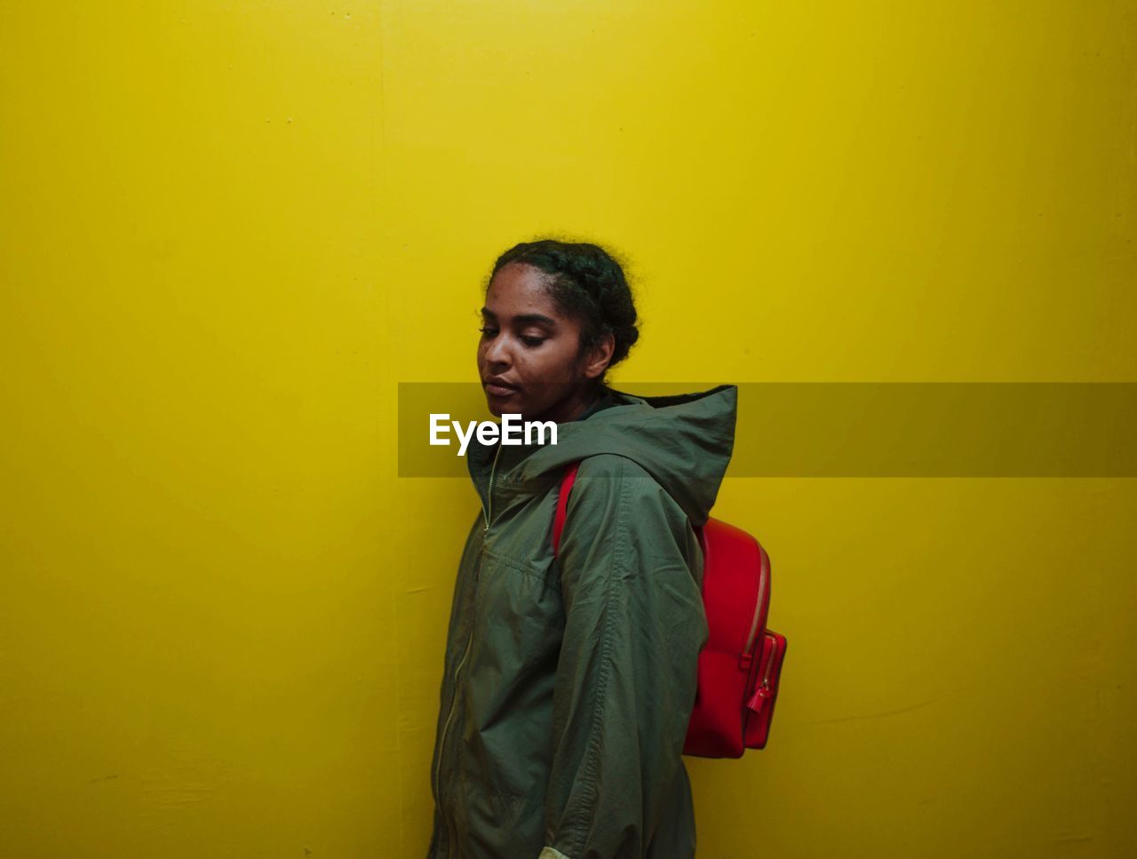 Teenage girl standing against yellow background