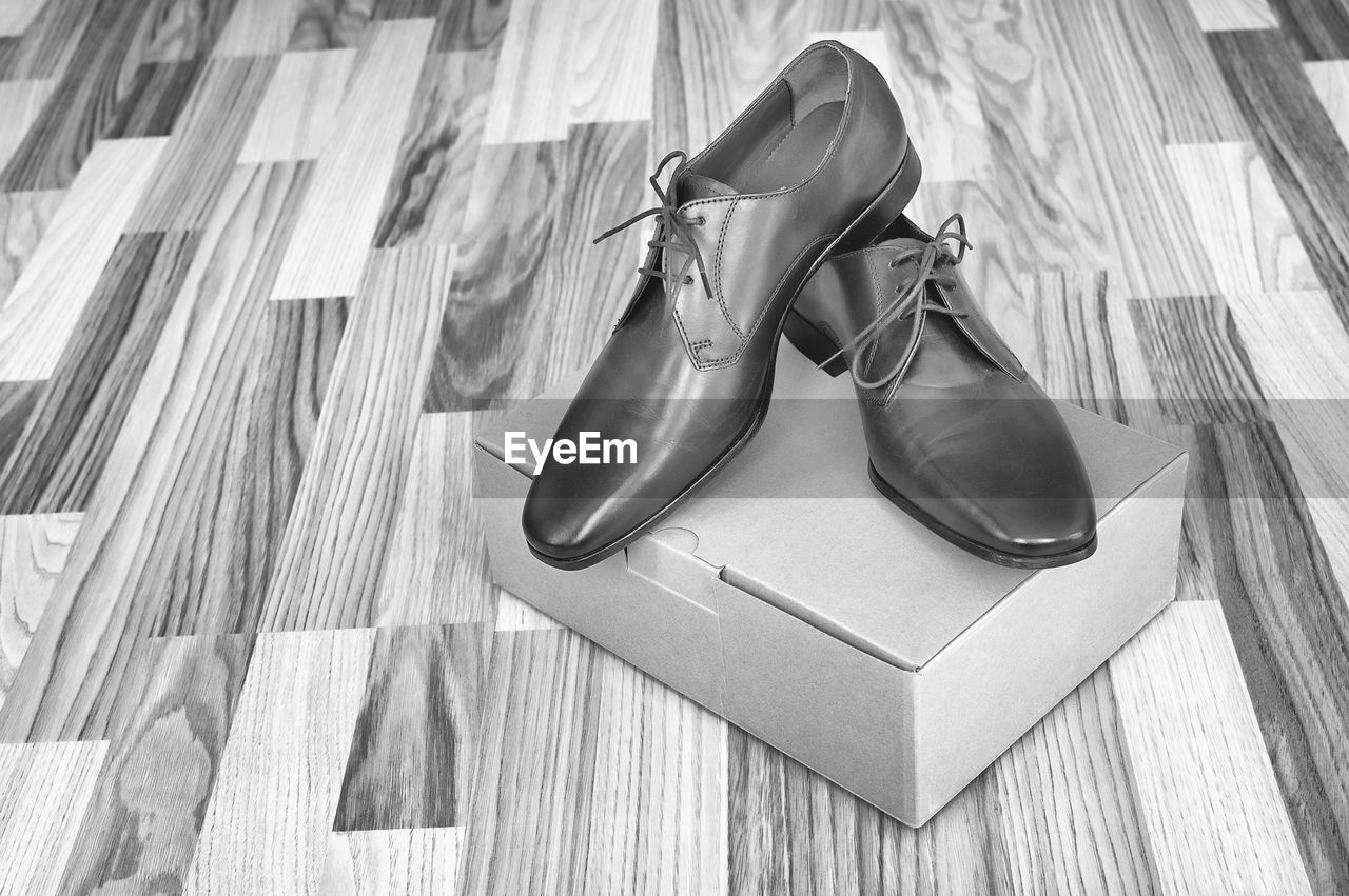 High angle view of formal shoes over box on hardwood floor
