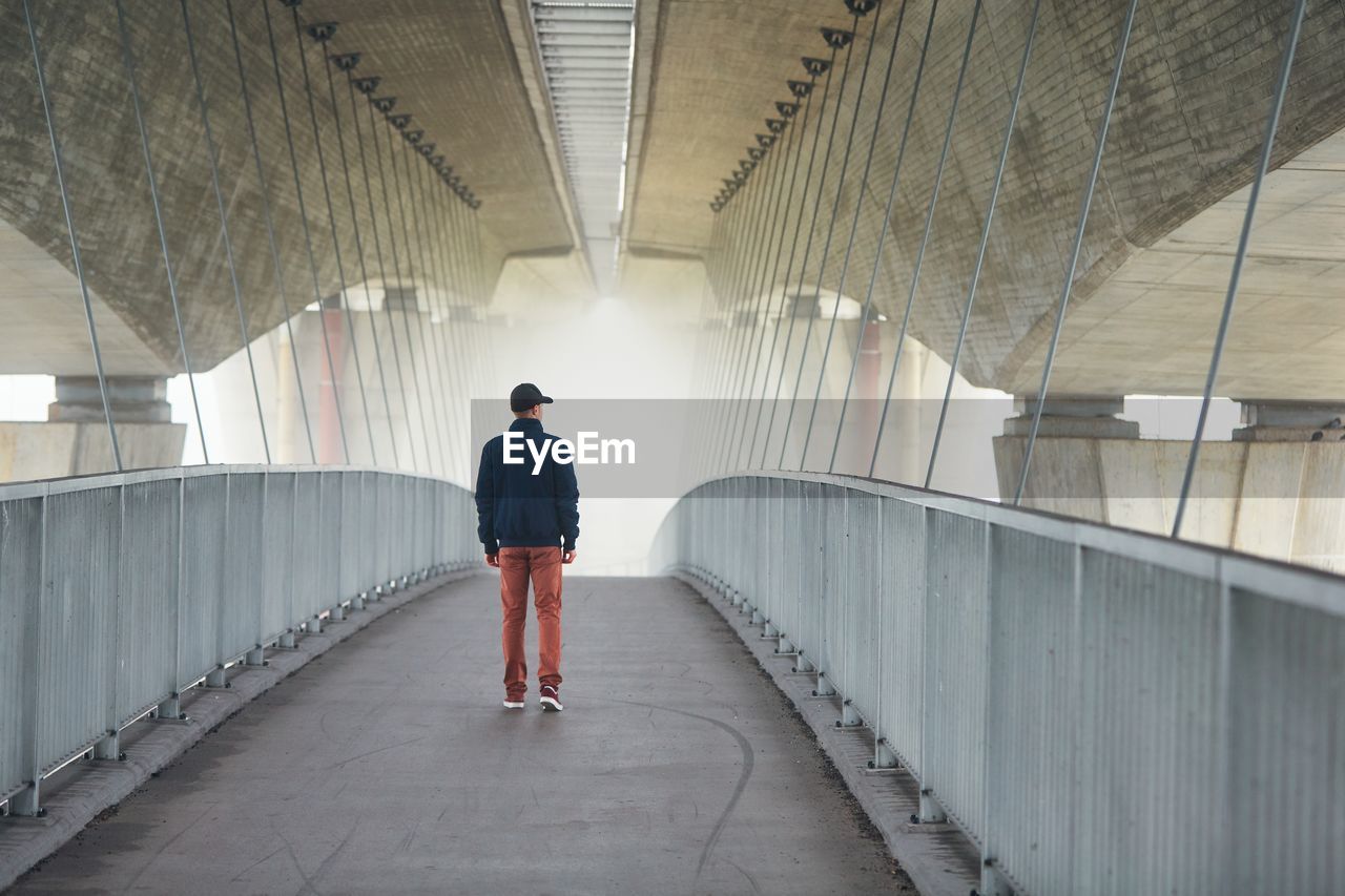 Rear view of young man standing on bridge