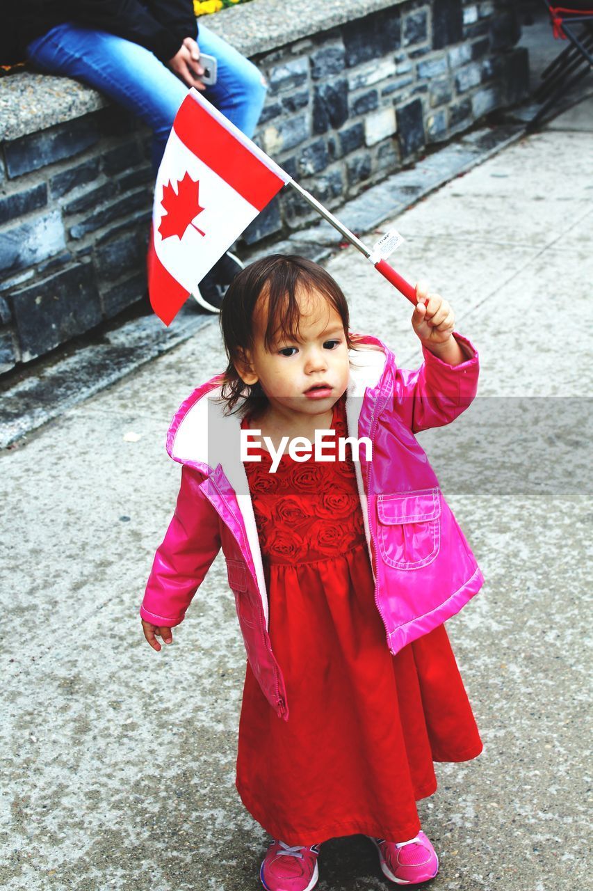 FULL LENGTH OF CUTE GIRL HOLDING PINK WHILE STANDING AGAINST UMBRELLA