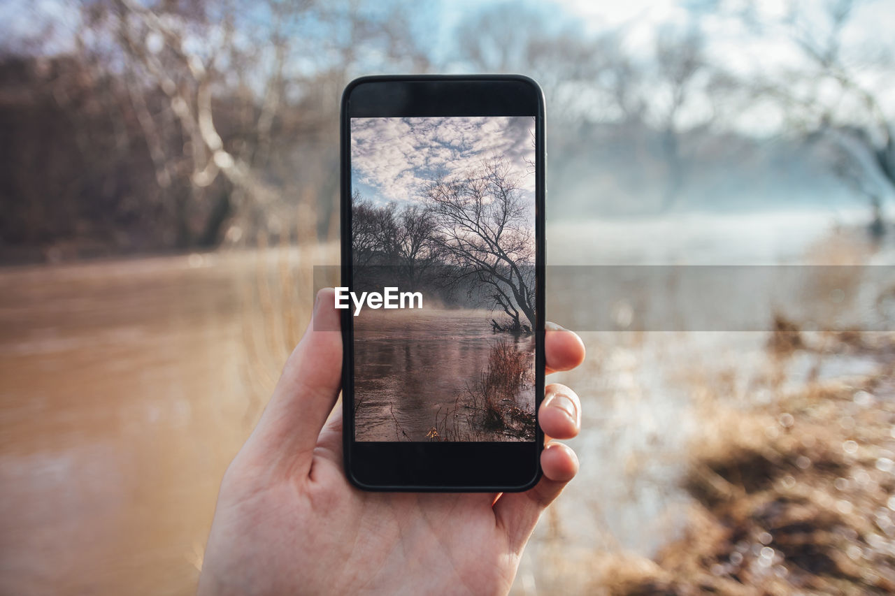 CLOSE-UP OF HAND HOLDING MOBILE PHONE WITH CAMERA