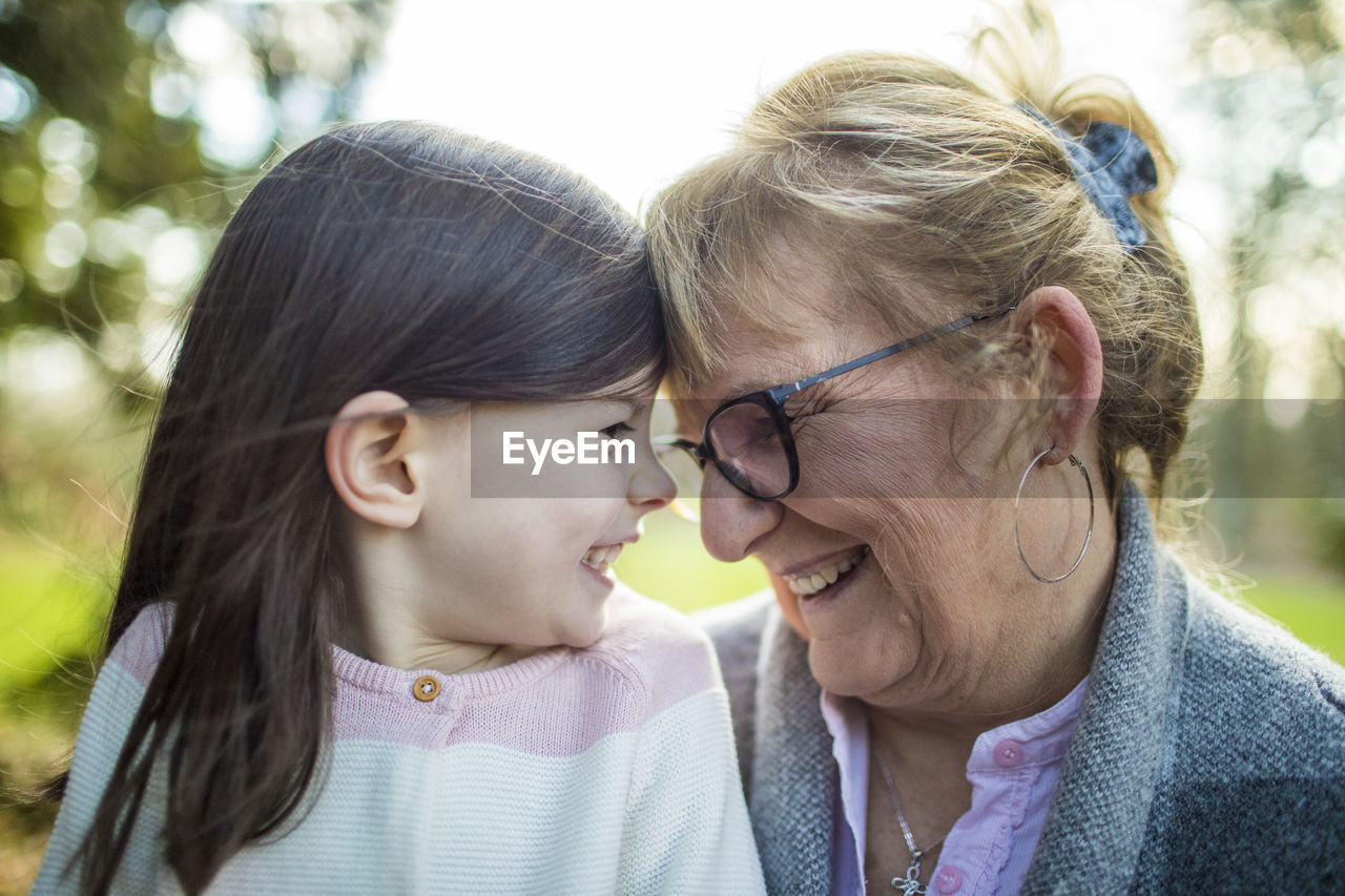 Grandma smiling at granddaughter in outdoor setting.