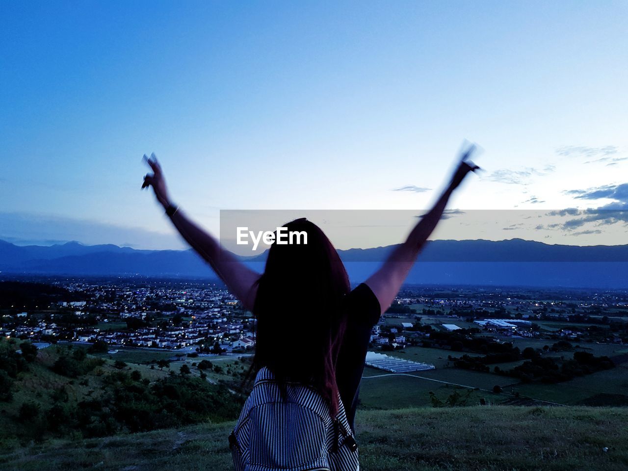 Rear view of woman standing against sky during sunset