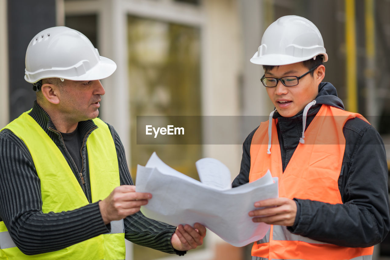 Engineers discussing while standing at construction site