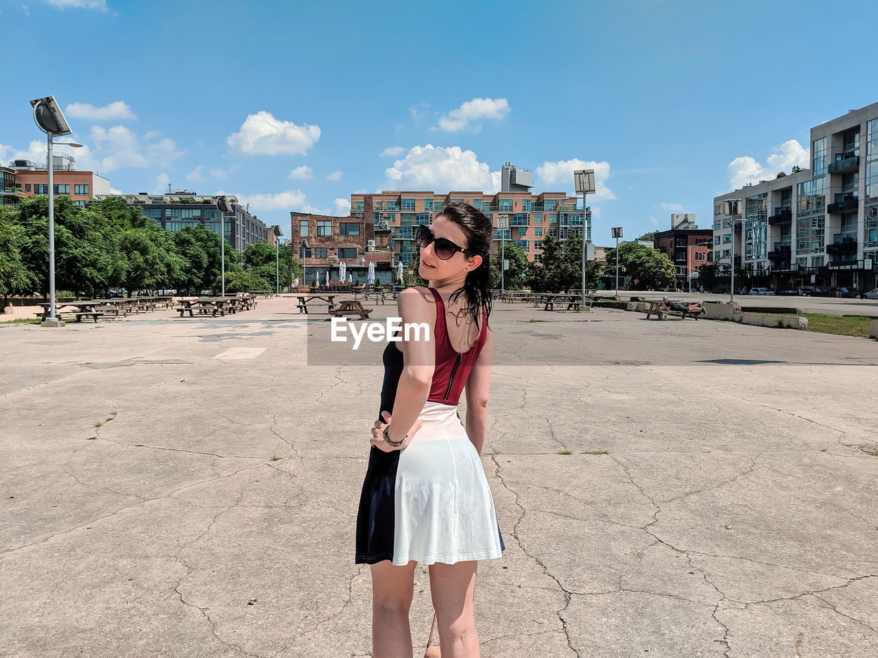 Portrait of young woman wearing sunglasses standing against built structure