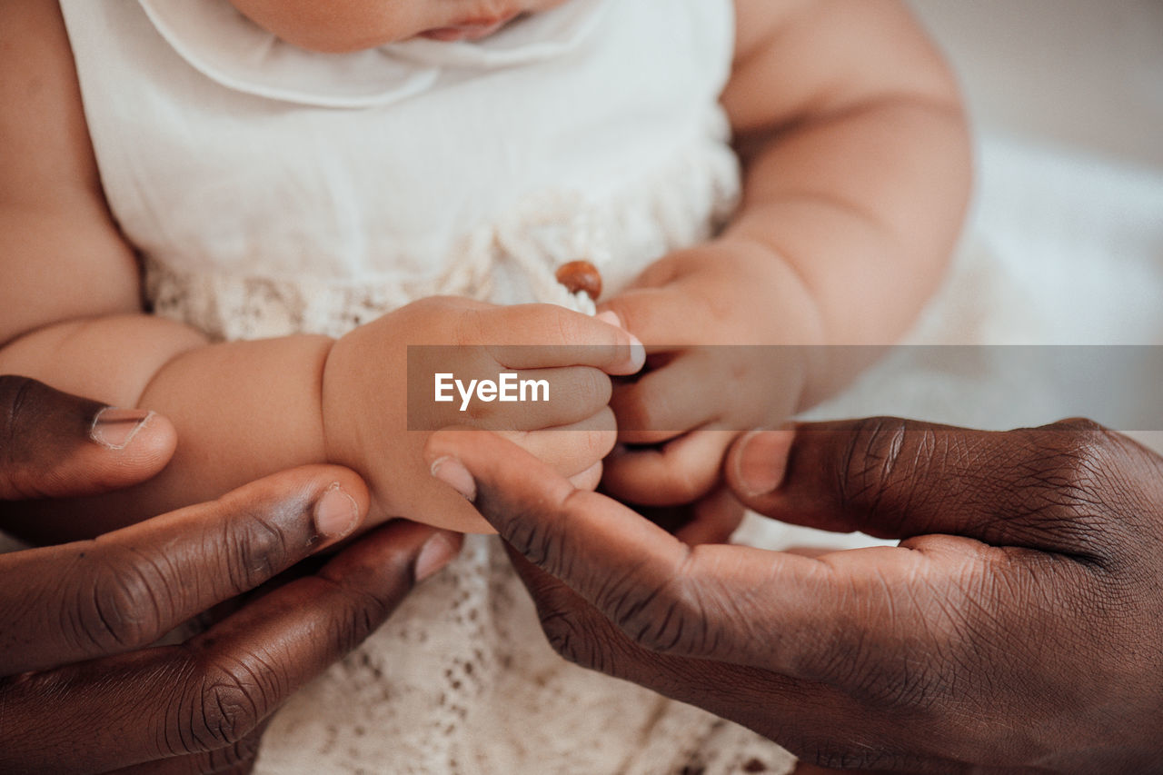 Midsection of woman holding baby hand