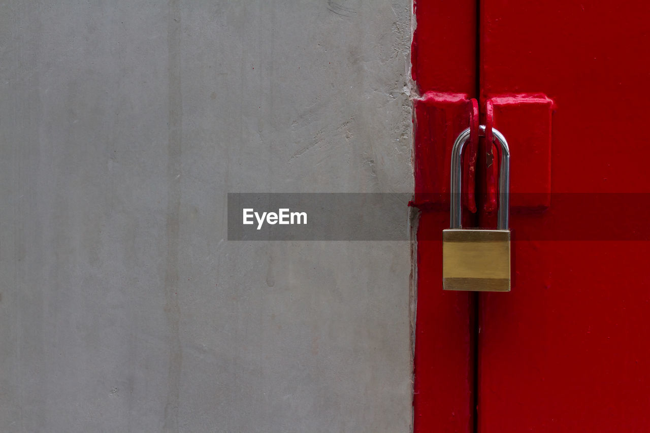 Textured of old dark cement wall and brass pad lock with strong gate red slide door and copy space.