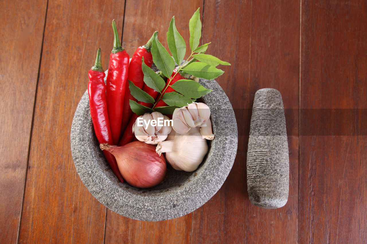 High angle view of spices with vegetables in mortar on wooden table