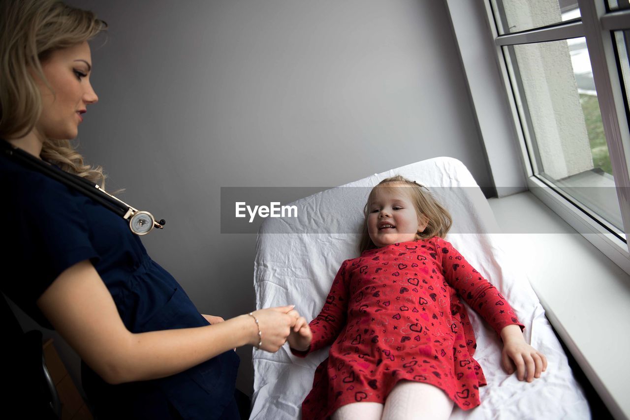 Pediatrician examining cute girl in medical clinic