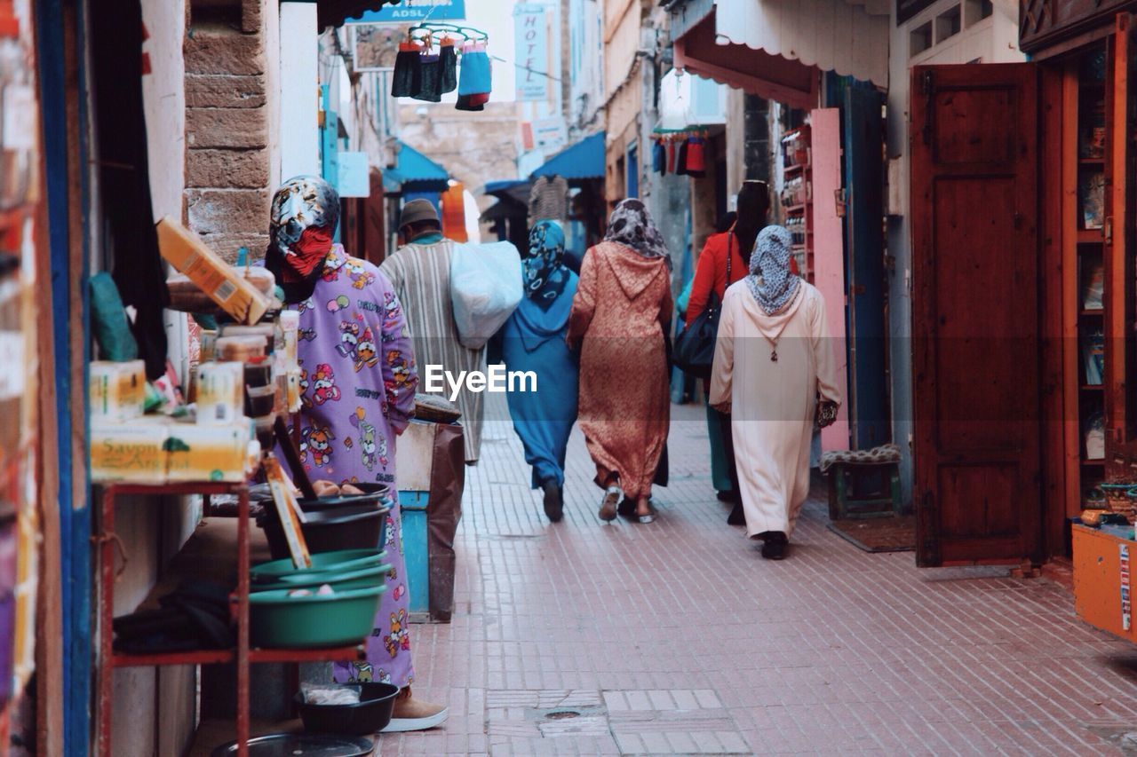 Rear view of people on footpath amidst buildings