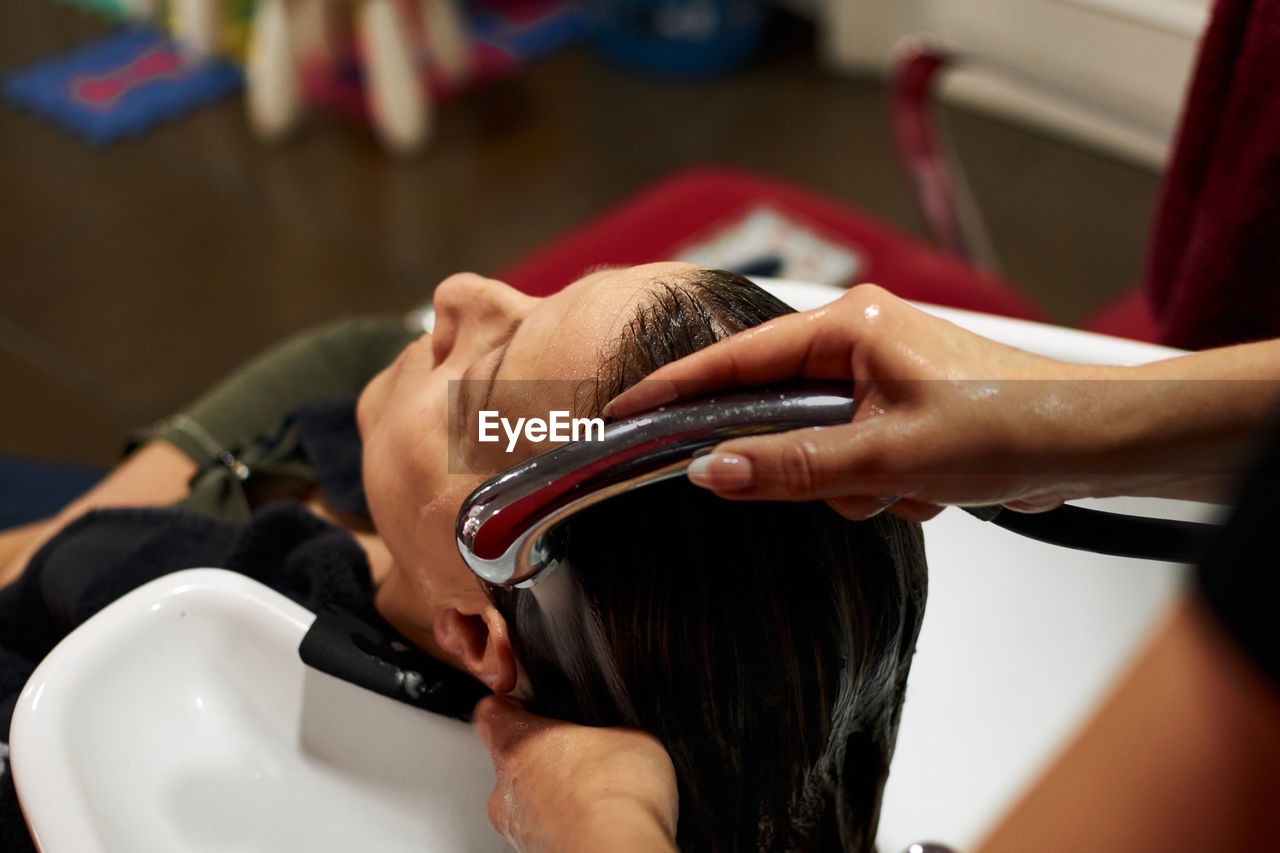 Hairdresser washes her client's hair in her salon