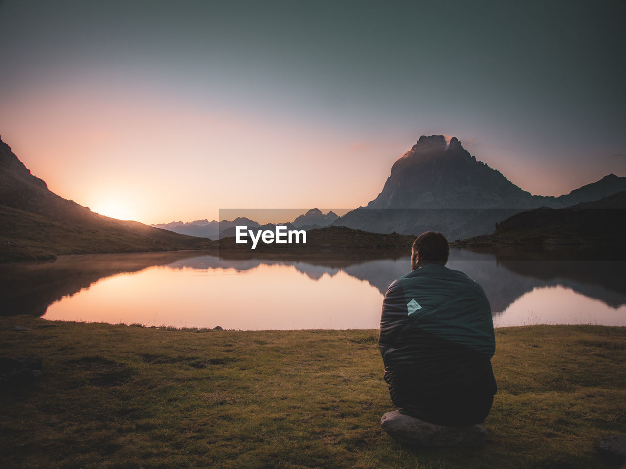 Rear view of man looking at mountains against sky during sunset