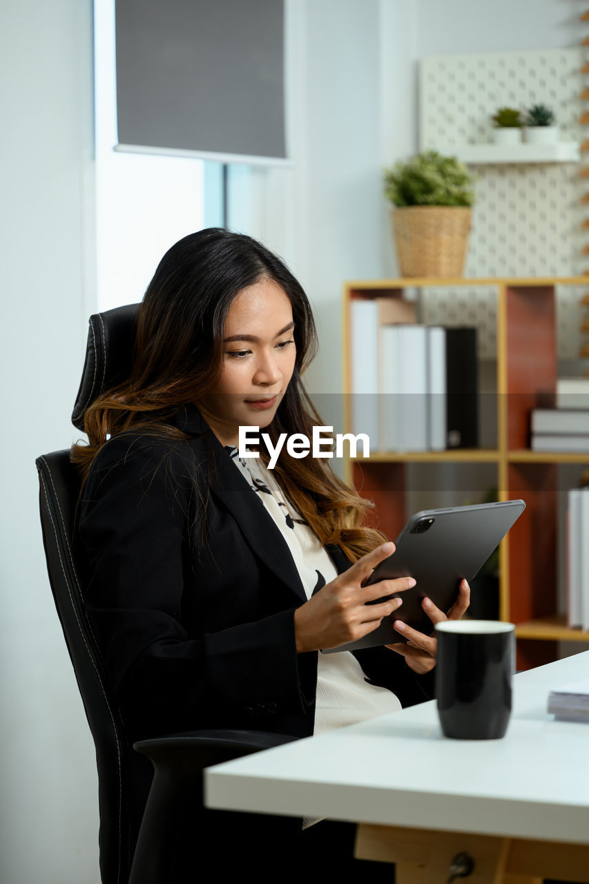 portrait of young businesswoman using laptop while sitting on table