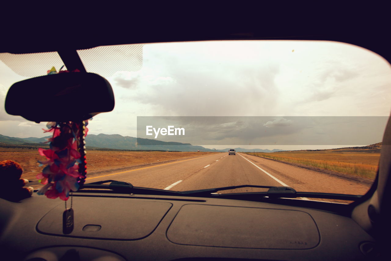 Country road against sky seen through car windshield