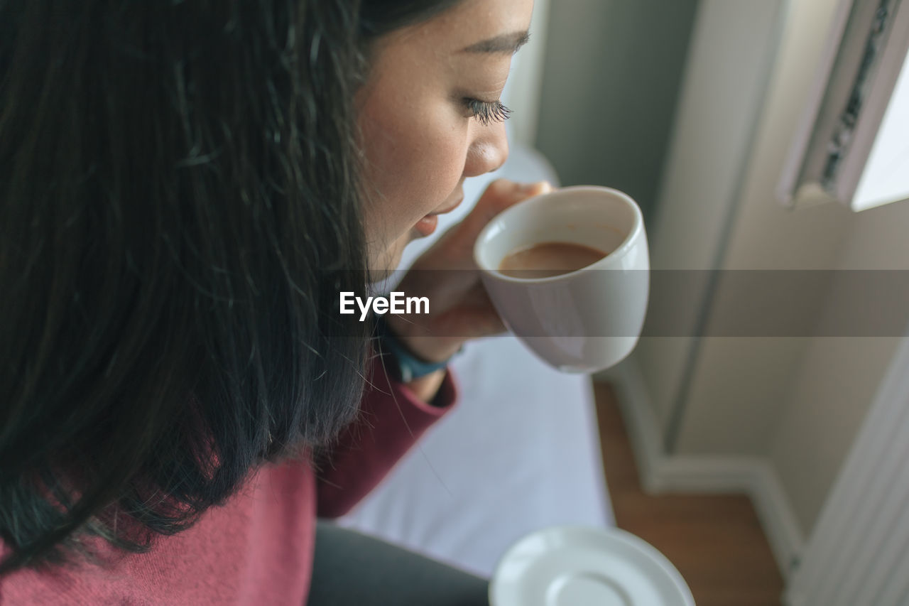 Close-up of woman drinking coffee at home