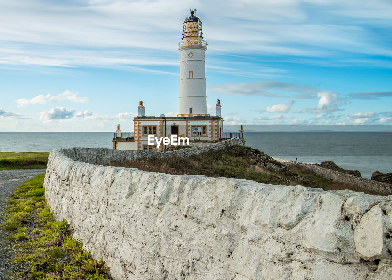 Scottish lighthouse by sea against sky