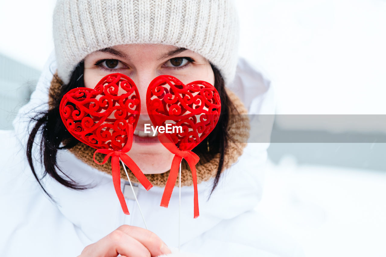 one person, portrait, red, clothing, adult, winter, looking at camera, emotion, women, lip, heart shape, young adult, headshot, cold temperature, human face, front view, human head, cap, positive emotion, hat, valentine's day, snow, fun, white, white background, food and drink, nose, female, moustache, food, happiness, lifestyles, indoors, smiling, holding, person