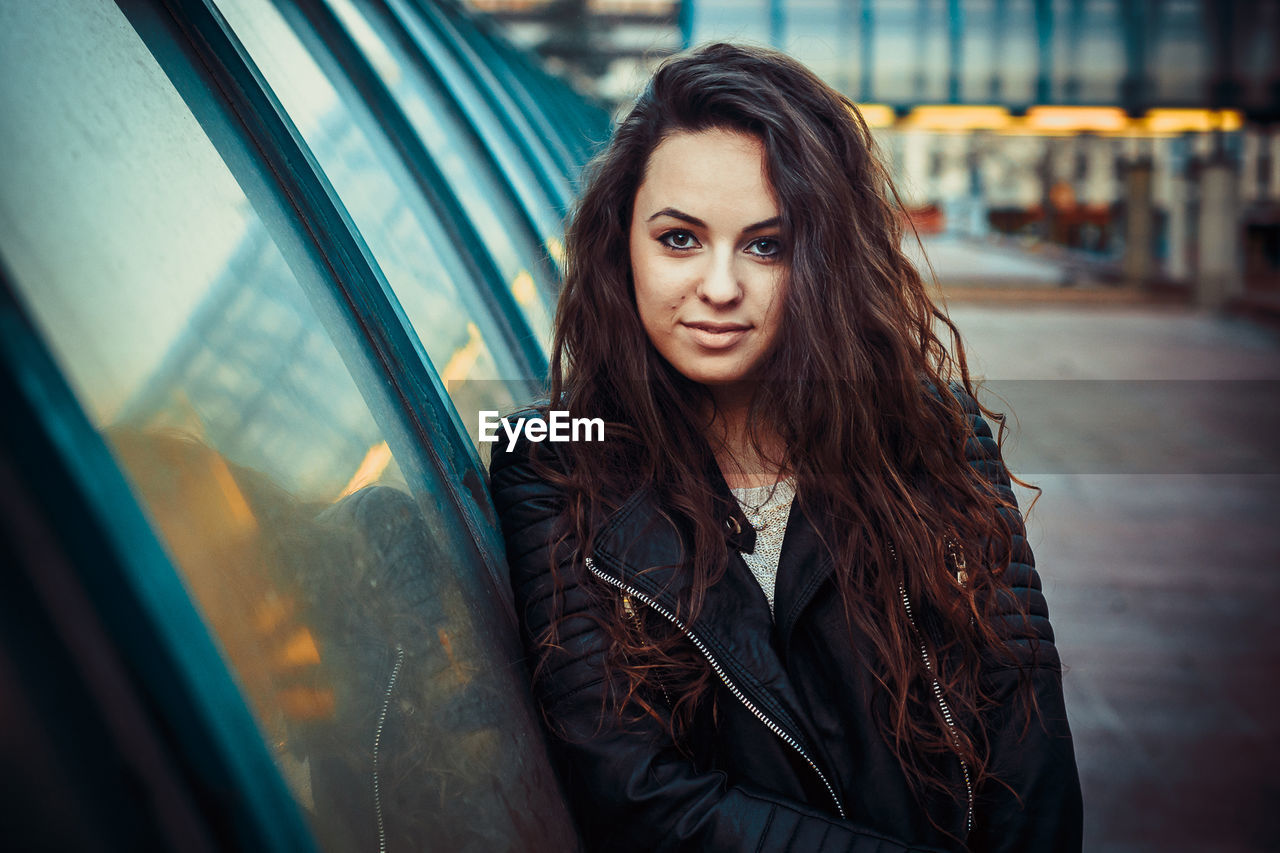 Portrait of young woman standing on street in city