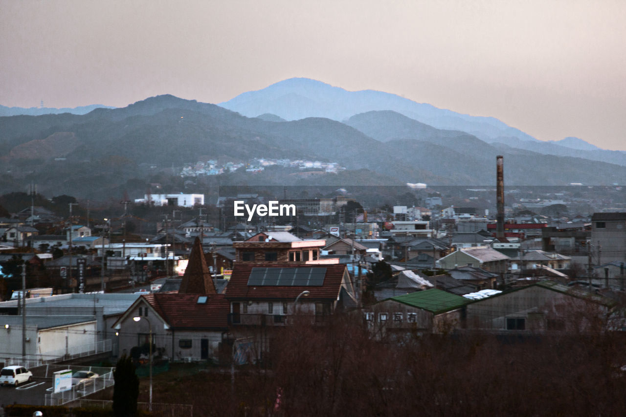 Scenic view of mountain range by town against clear sky at dawn