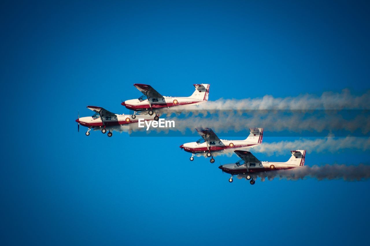 LOW ANGLE VIEW OF AIRSHOW AGAINST CLEAR BLUE SKY