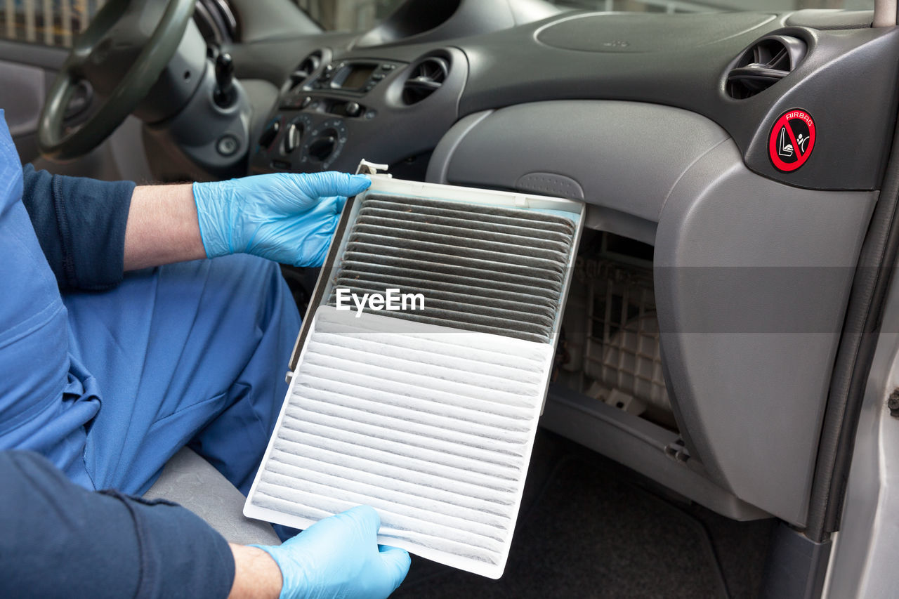 Midsection of man repairing air conditioner in car