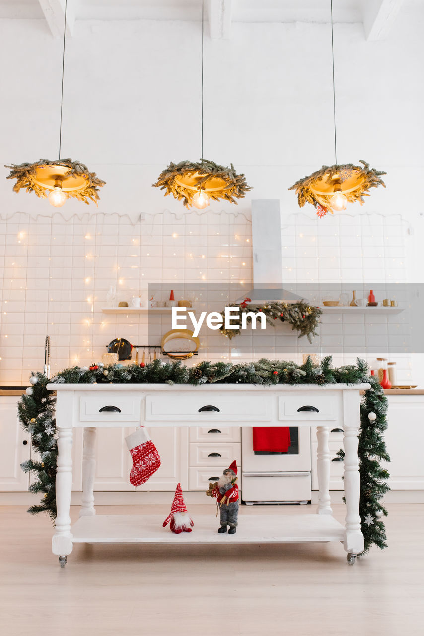 White wooden kitchen interior, kitchen utensils and red christmas decor with lights