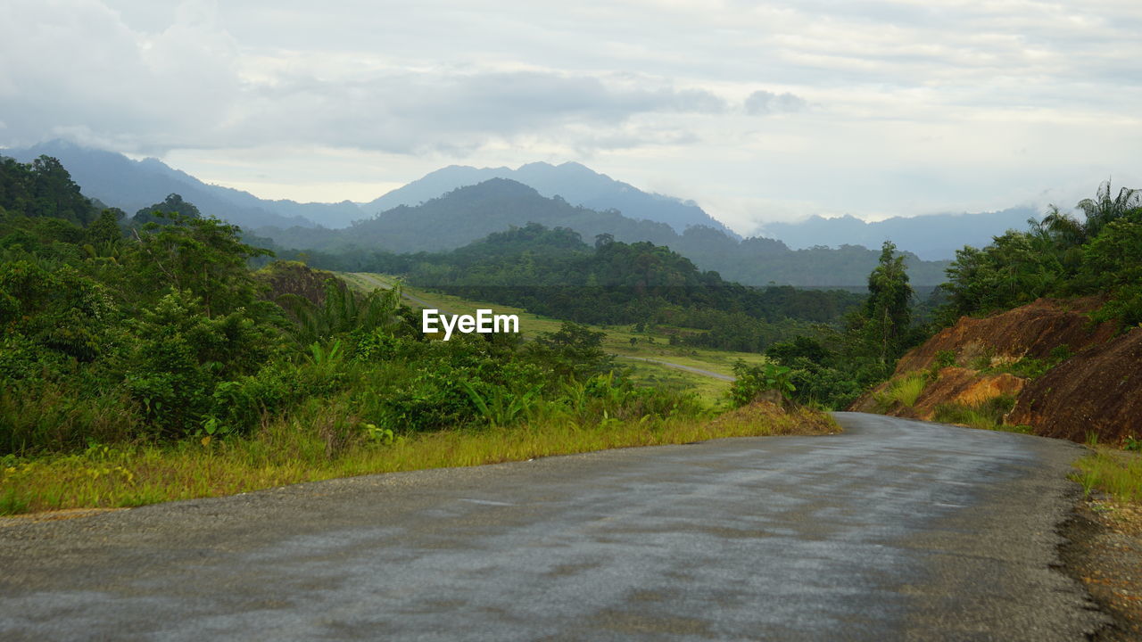 Road by mountains against sky