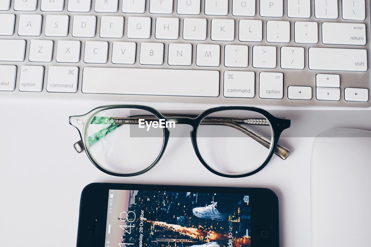 Directly above shot of eyeglasses and smart phone on laptop