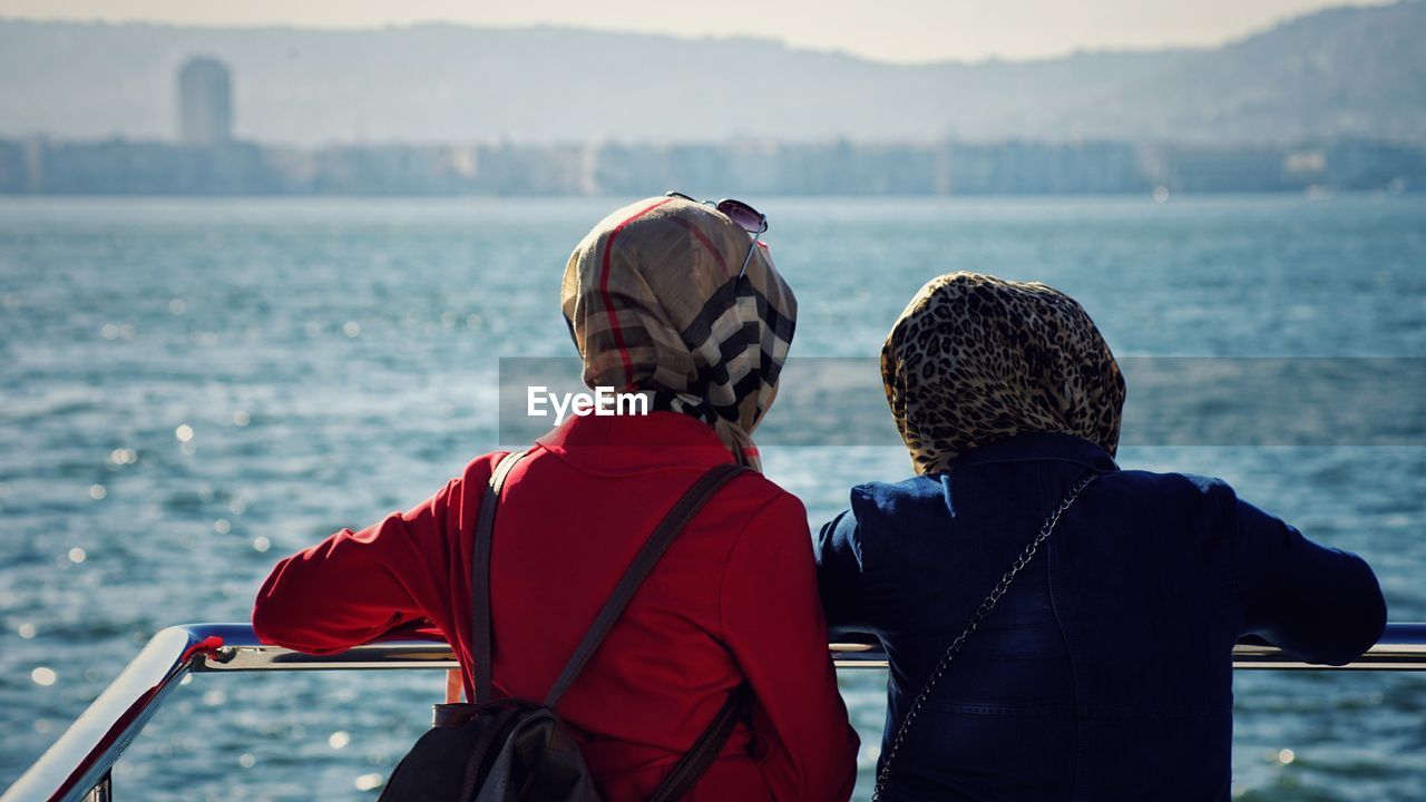 Rear view of women wearing headscarf looking at sea