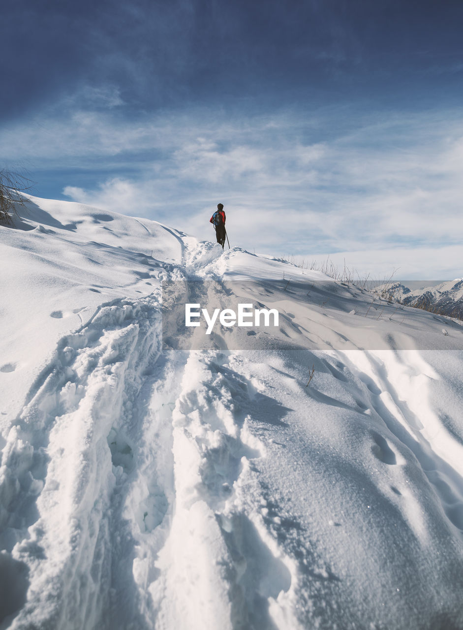 Rear view of man on snow covered mountain against sky