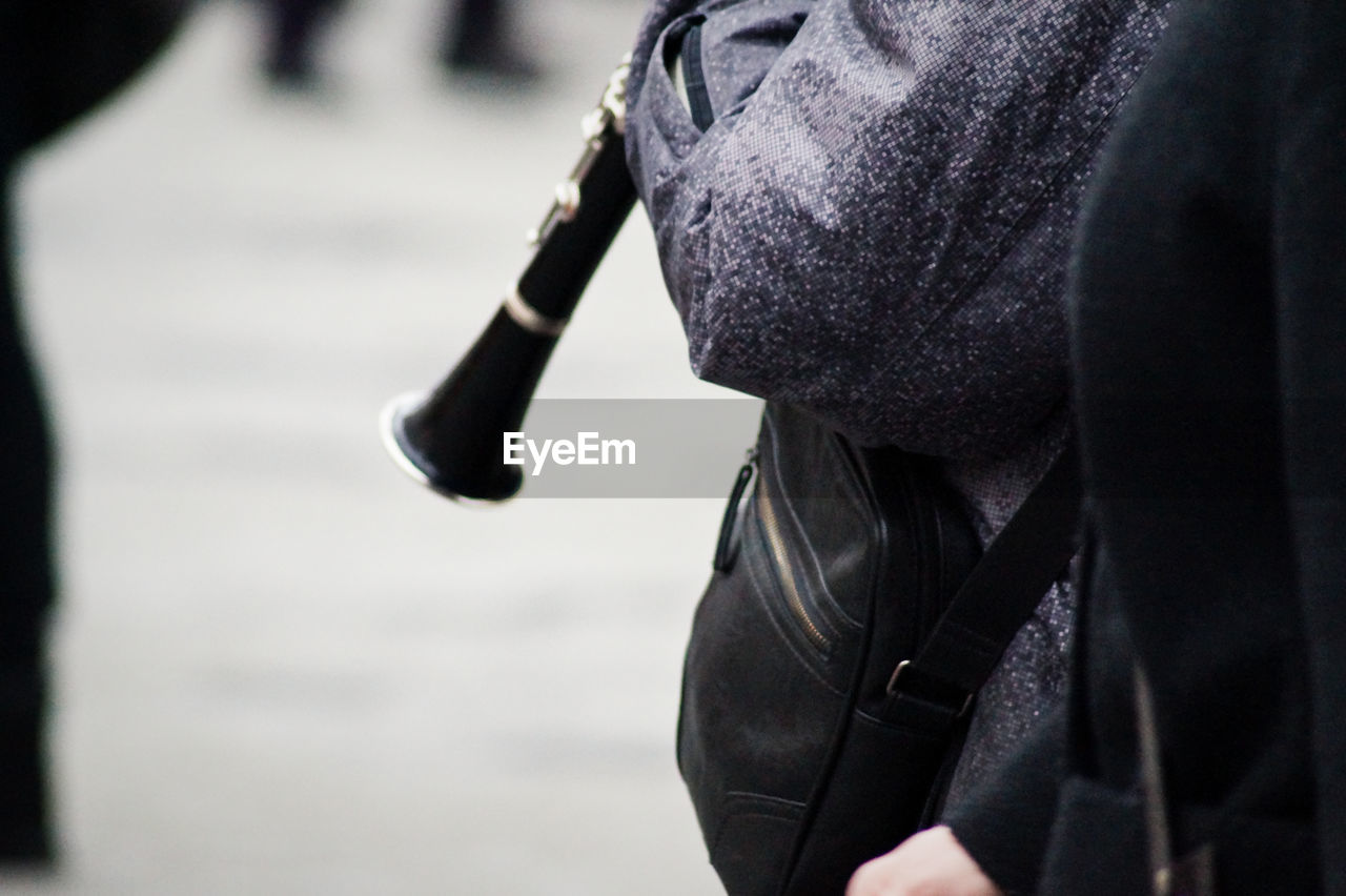 Close-up of person holding flute and standing on street