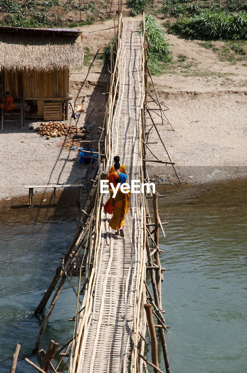 High angle view of monks working on footbridge over river