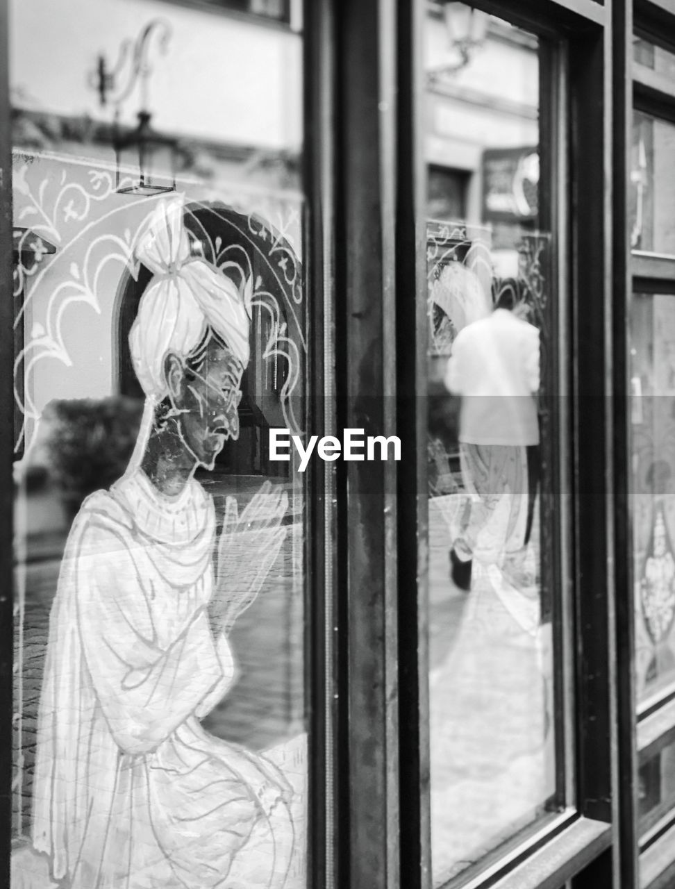 REFLECTION OF MAN IN GLASS WINDOW OF BUILDING