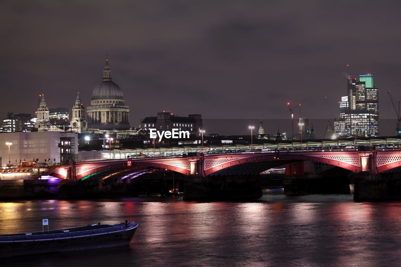 Blackfriars bridge over thames river in illuminated city at night