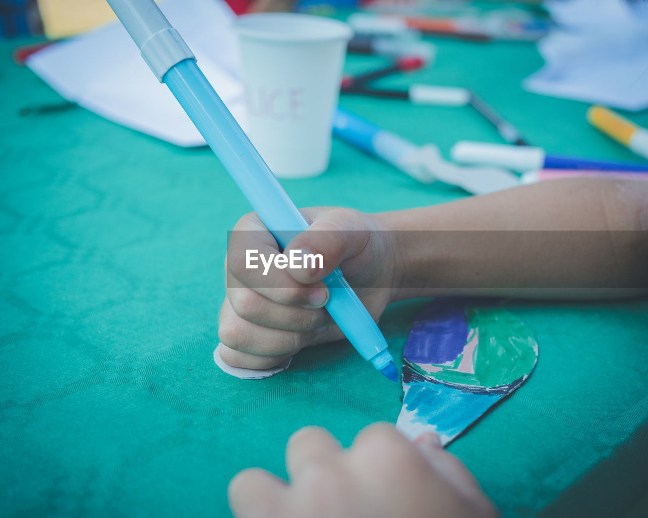 Cropped hand of person coloring over table