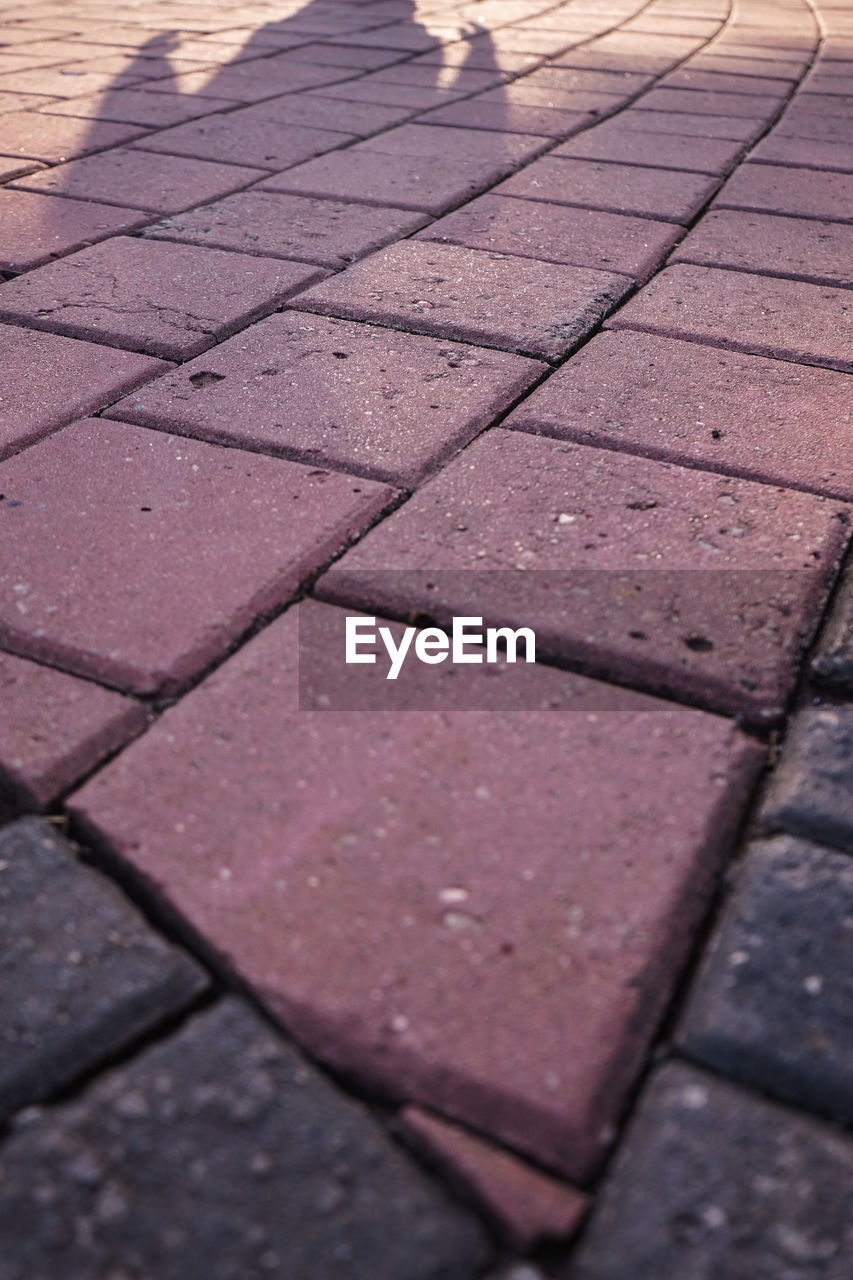 HIGH ANGLE VIEW OF PAVING STONE ON FOOTPATH