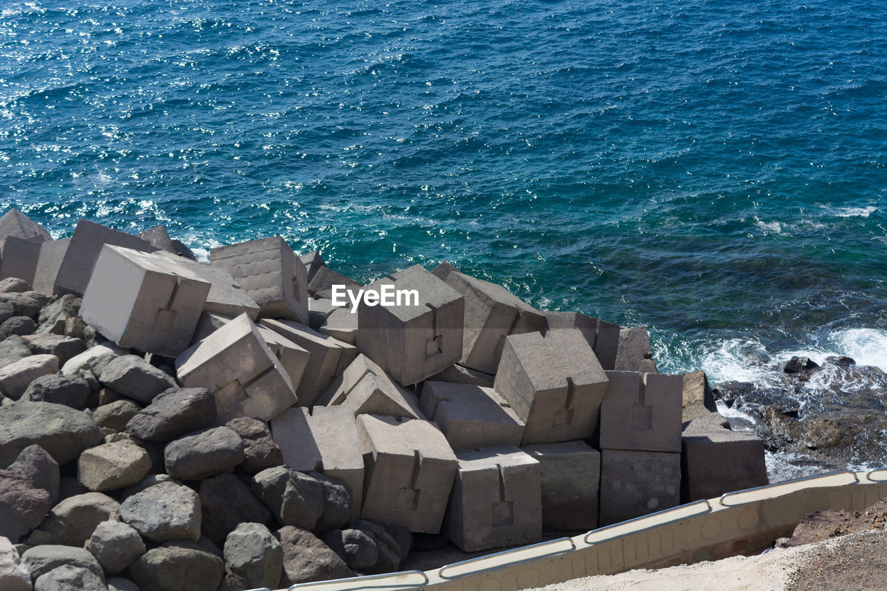 water, sea, rock, nature, terrain, ocean, coast, day, no people, land, high angle view, beach, shore, breakwater, beauty in nature, outdoors, architecture, blue, wave, sunlight, motion