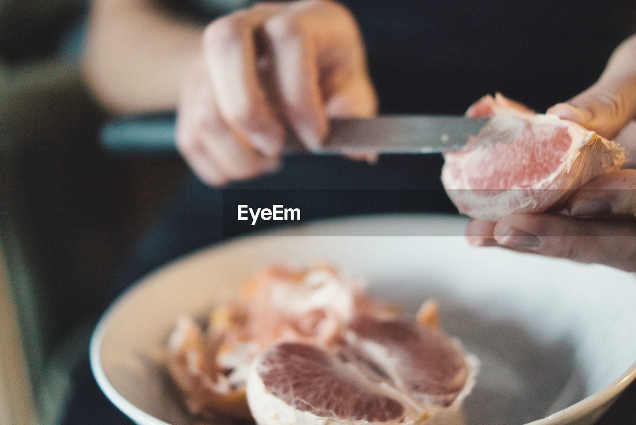 Close-up of hand preparing grapefruit 