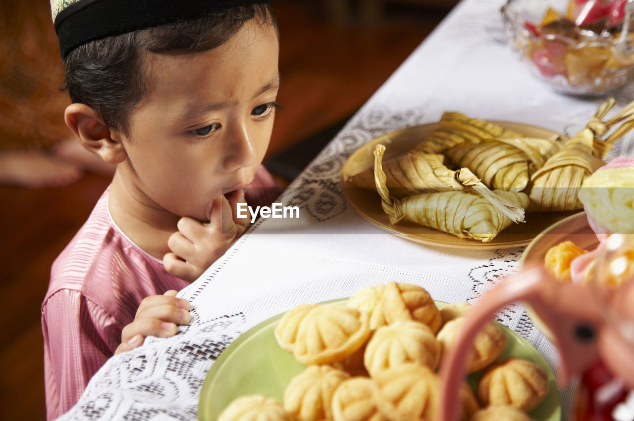 Boy standing beside table with food in plates