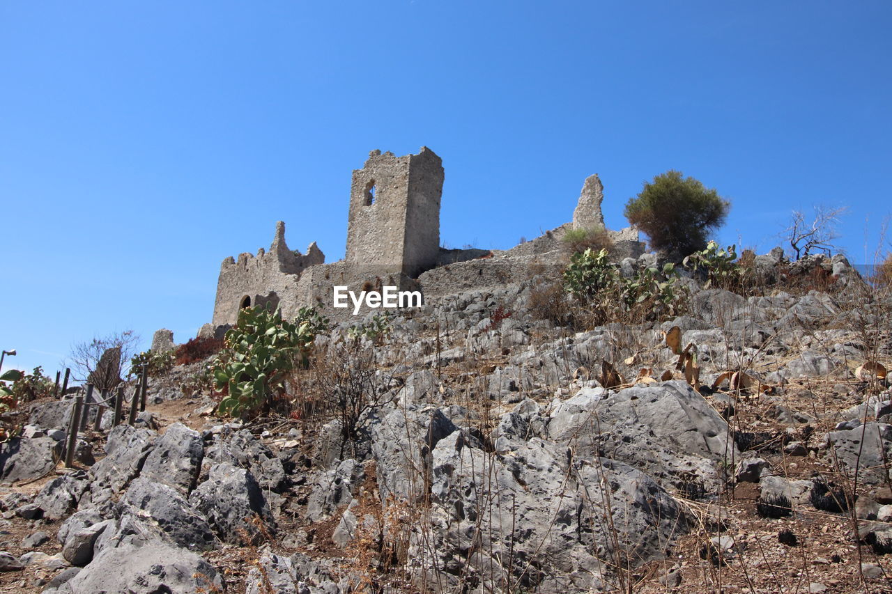 history, sky, the past, architecture, ruins, nature, clear sky, rock, travel destinations, blue, travel, ancient, built structure, no people, plant, land, fort, tree, building, old ruin, tourism, building exterior, outdoors, sunny, landscape, scenics - nature, mountain, ancient history, day, low angle view, wall, castle, environment, old, non-urban scene