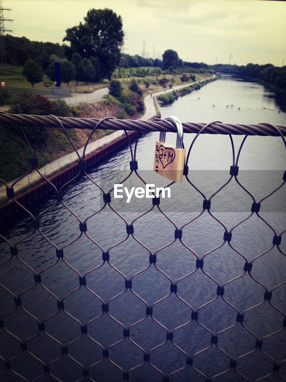 Lock on fence over river against sky