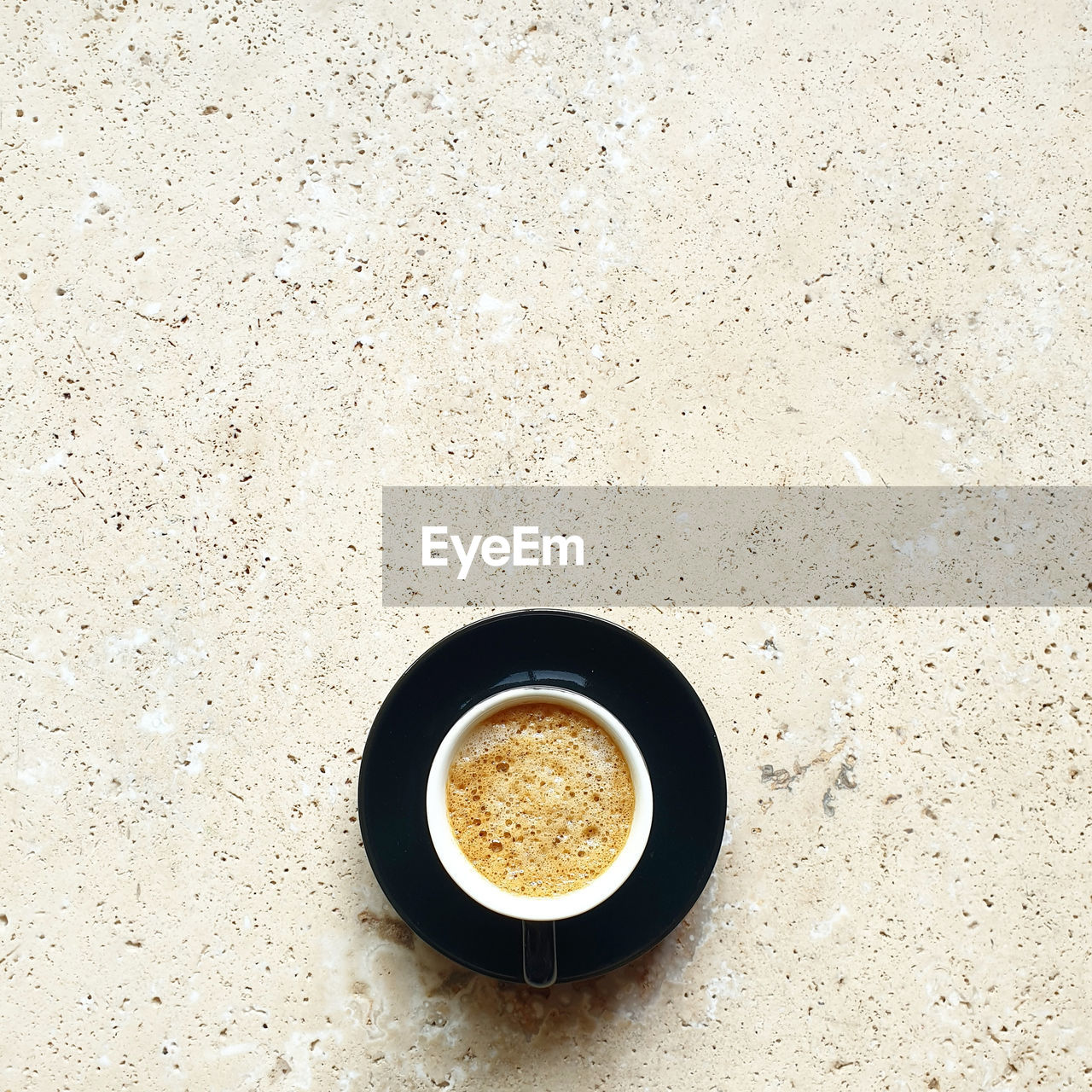 HIGH ANGLE VIEW OF COFFEE CUP ON TABLE AGAINST WALL