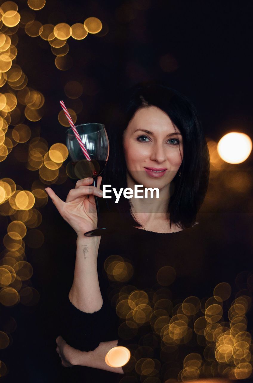 Girl with a glass of wine and a striped straw in the lights.