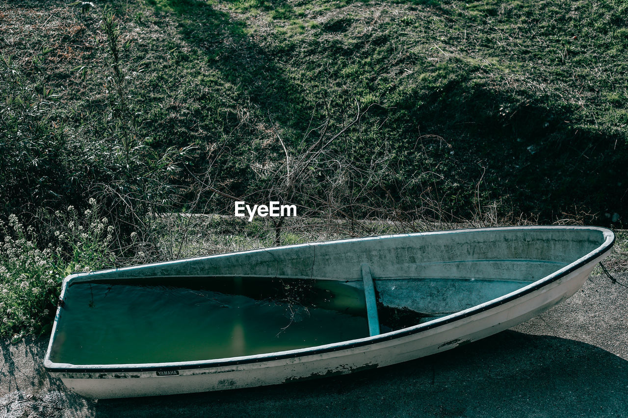 High angle view of boat filled with water moored by field