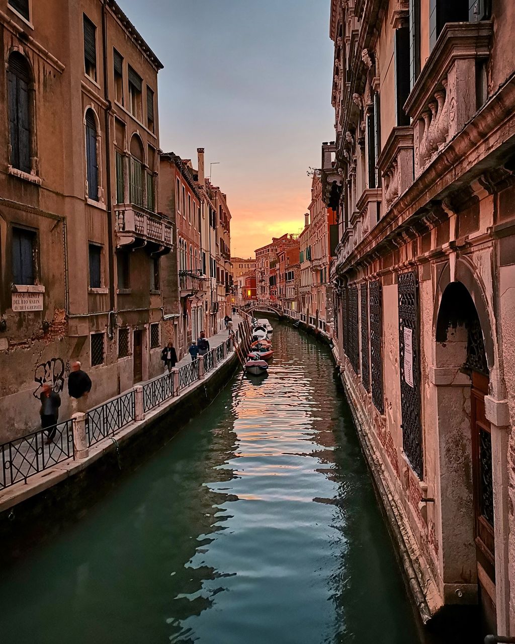 BRIDGE OVER CANAL AMIDST BUILDINGS AGAINST SKY