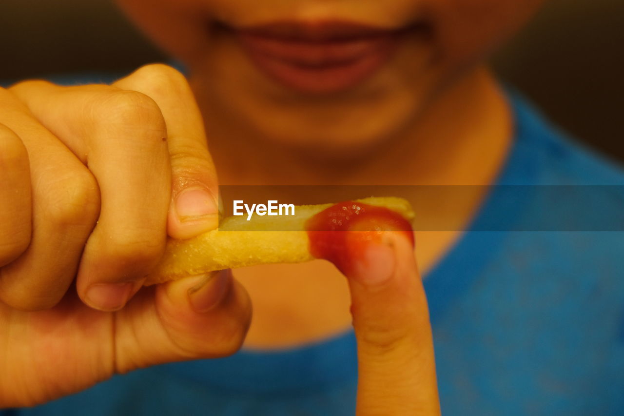 Midsection of boy eating french fries