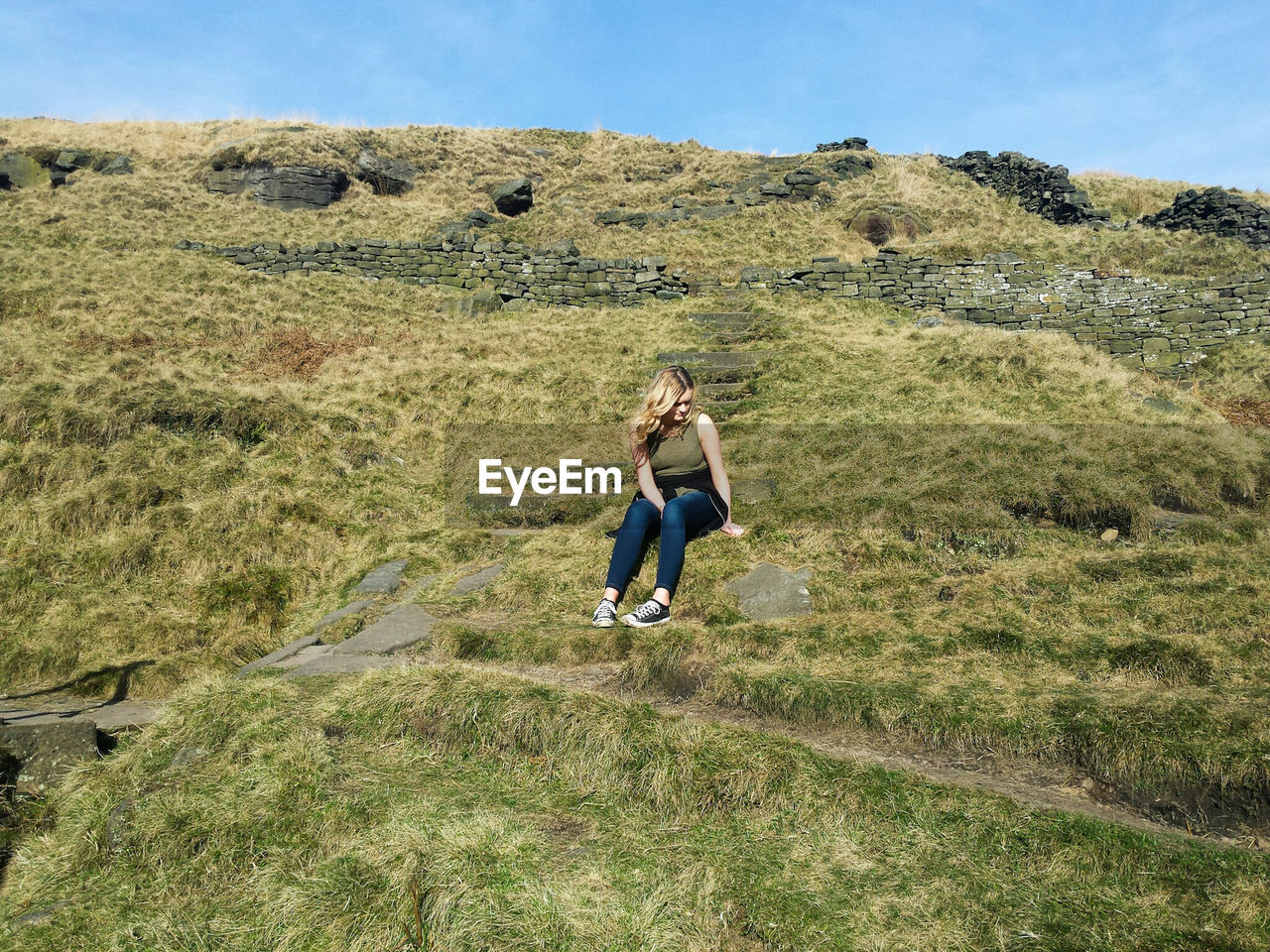 Full length of young woman sitting on mountain