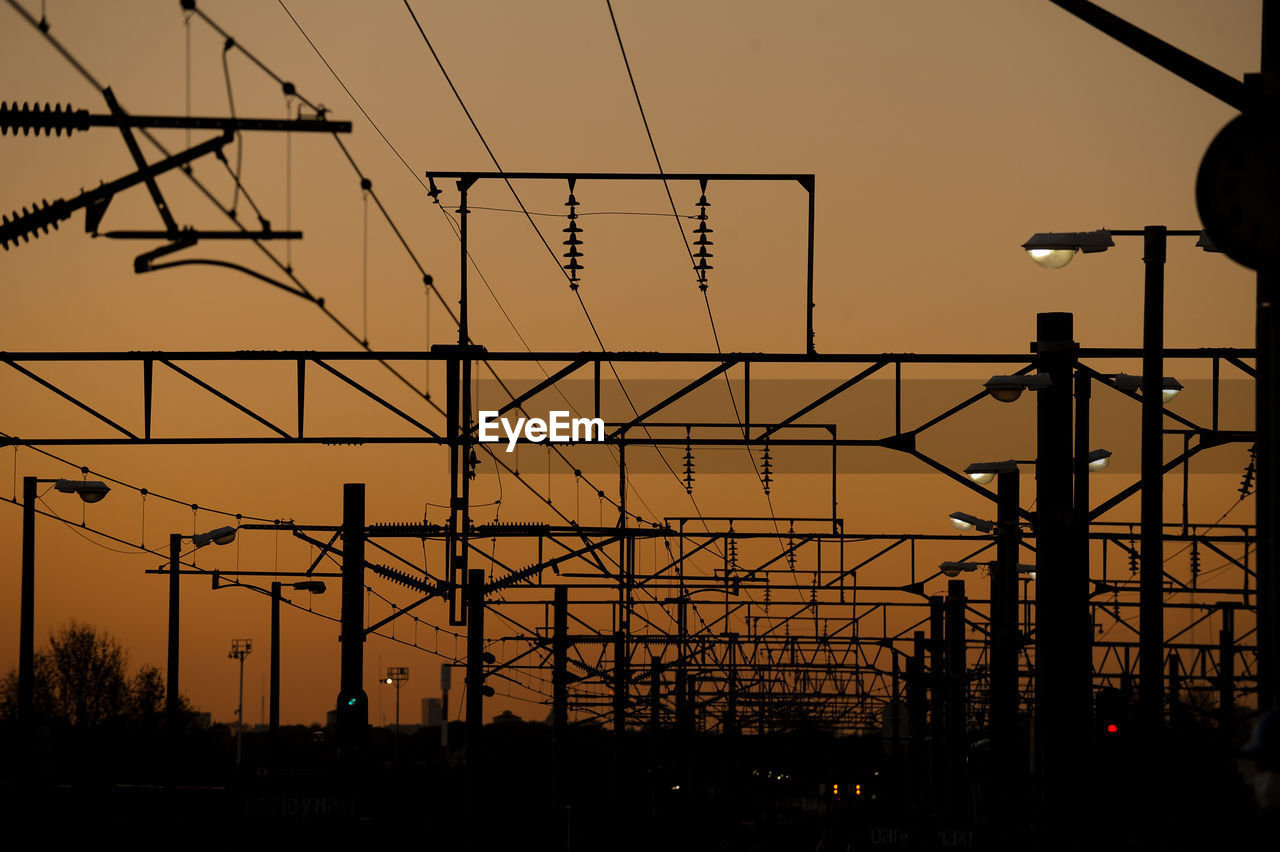 Low angle view of silhouette electricity pylon against sky during sunset